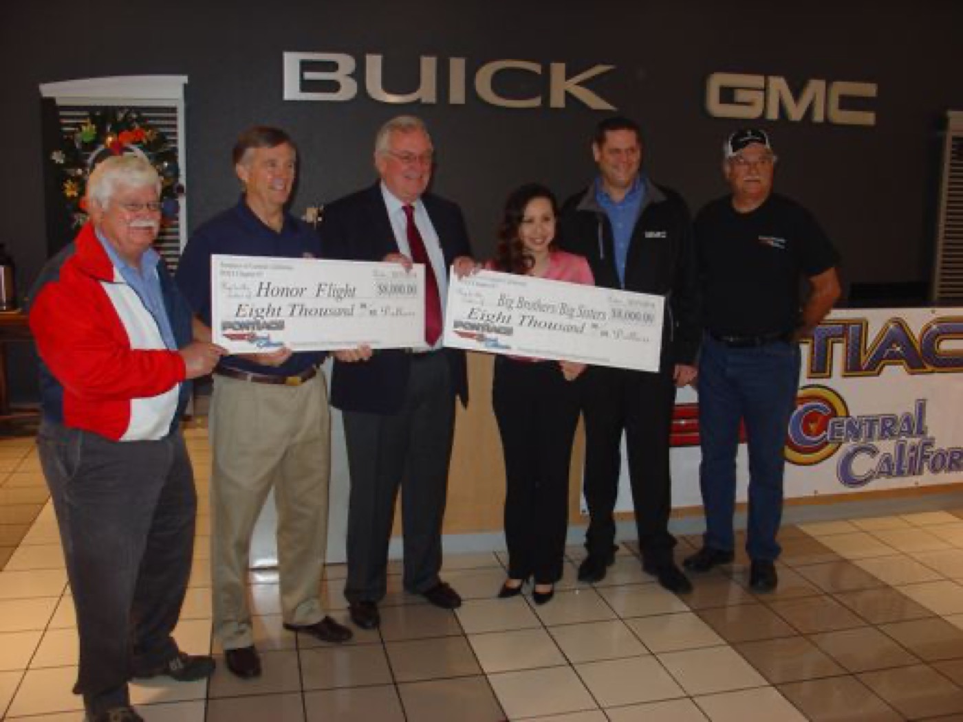 Members present big charity checks together, all smiles