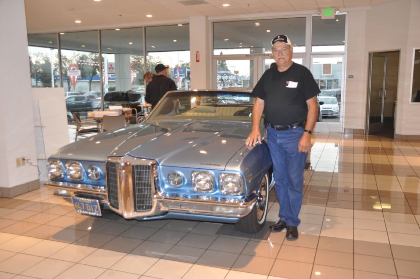 Member poses with blue Pontiac convertible
