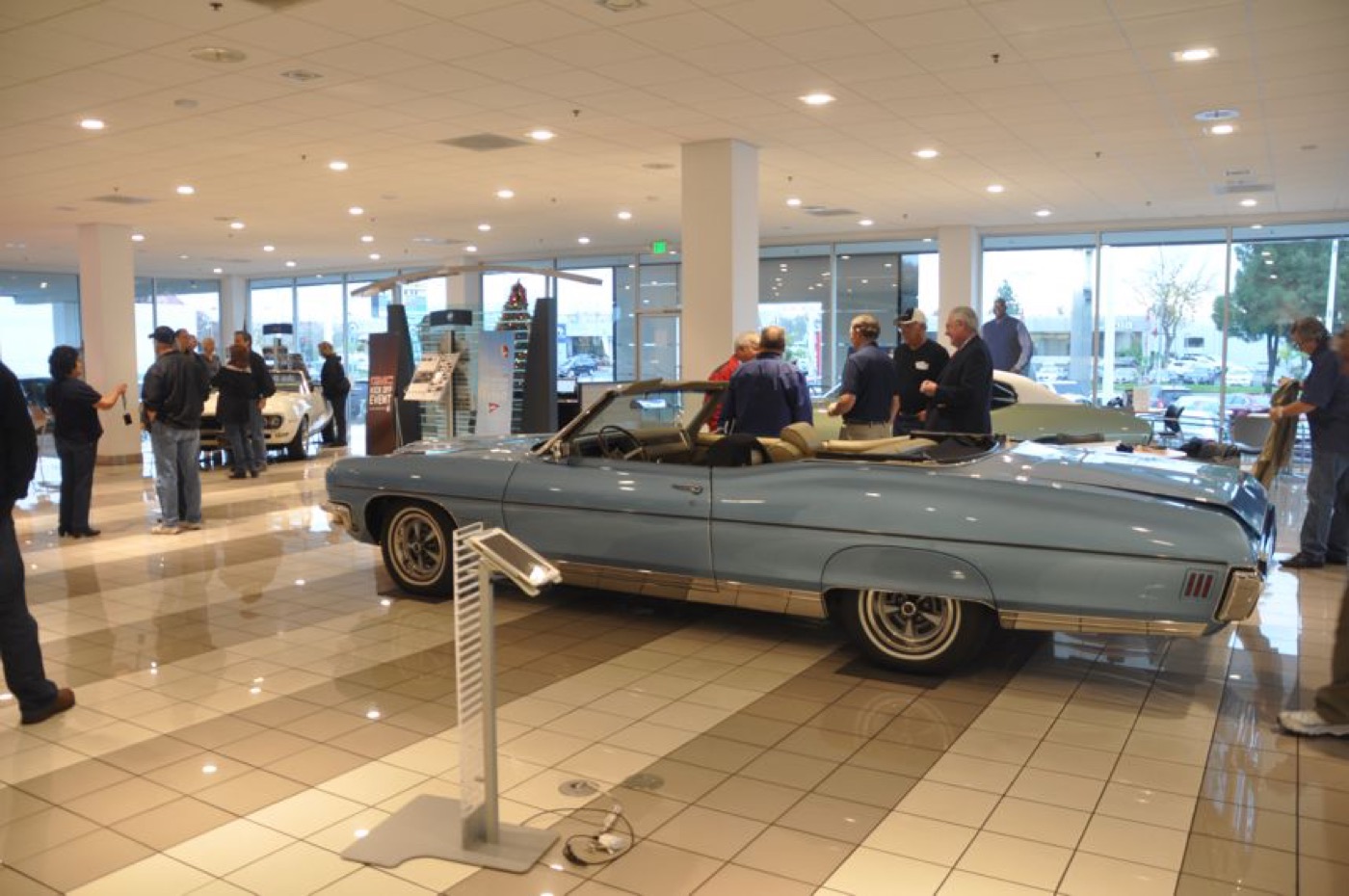 Blue convertible centered in busy showroom