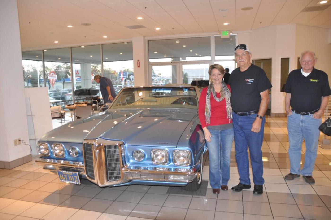 Members beside gleaming blue Pontiac Grand Prix