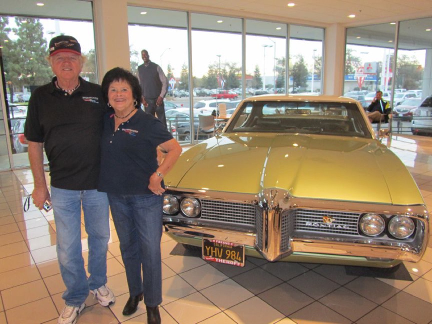 Smiling couple with golden Pontiac convertible